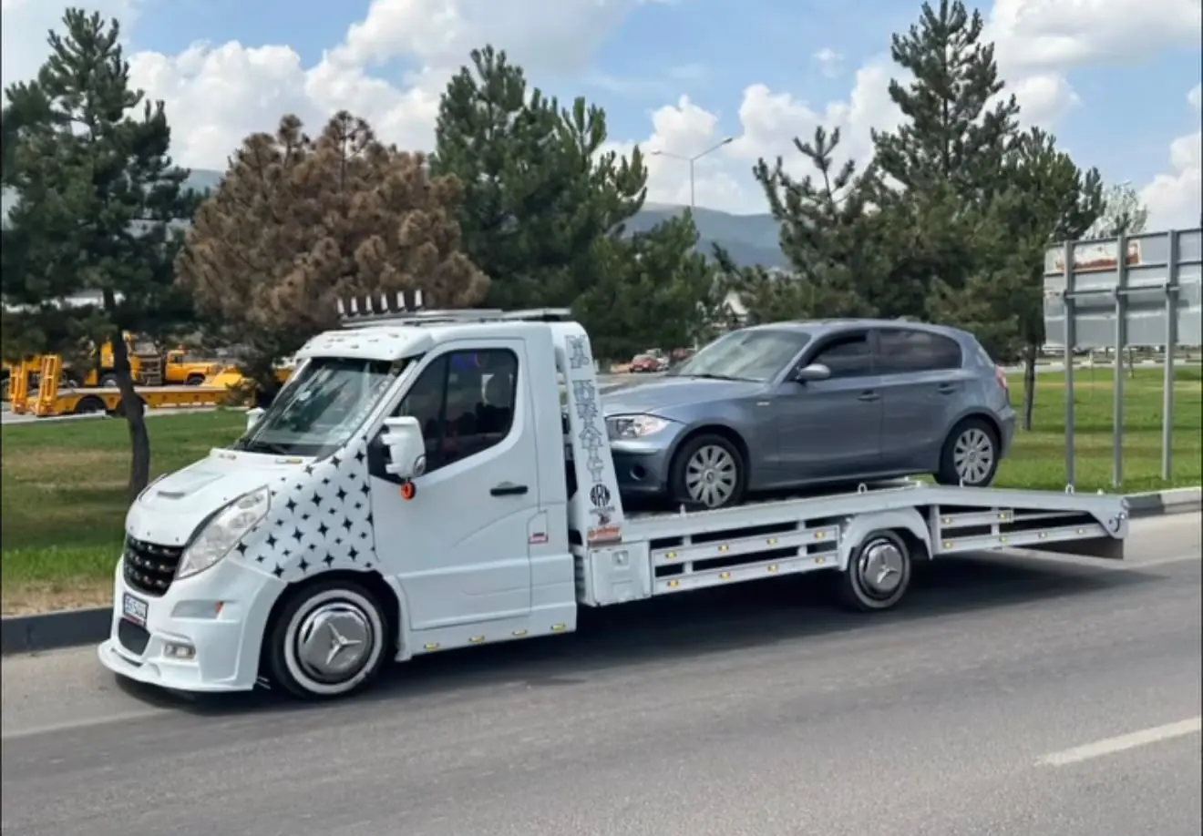 Beyaz platformlu çekici üzerinde taşınan gri binek otomobil